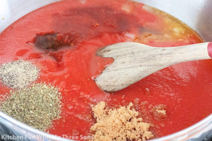 将番茄酱与香料一起搅拌，里面有一个木勺的大锅。