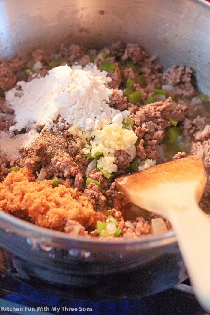 碎牛肉，洋葱，大蒜，绿色甜椒，红糖，盐，胡椒和面粉，在一个大锅里用木勺。