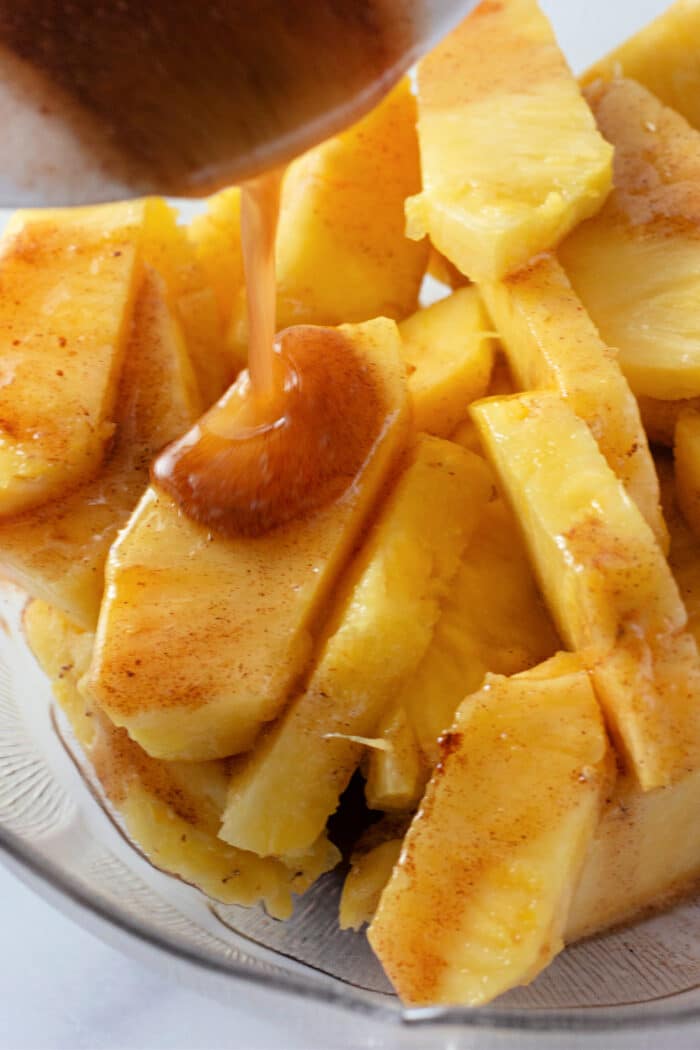 浇注熔化的黄油，枫糖浆和肉桂在新鲜的菠萝切片。