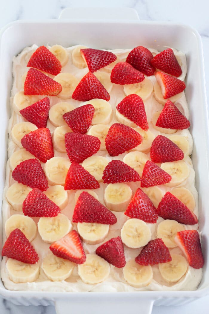 将草莓和香蕉放在奶油芝士层上。