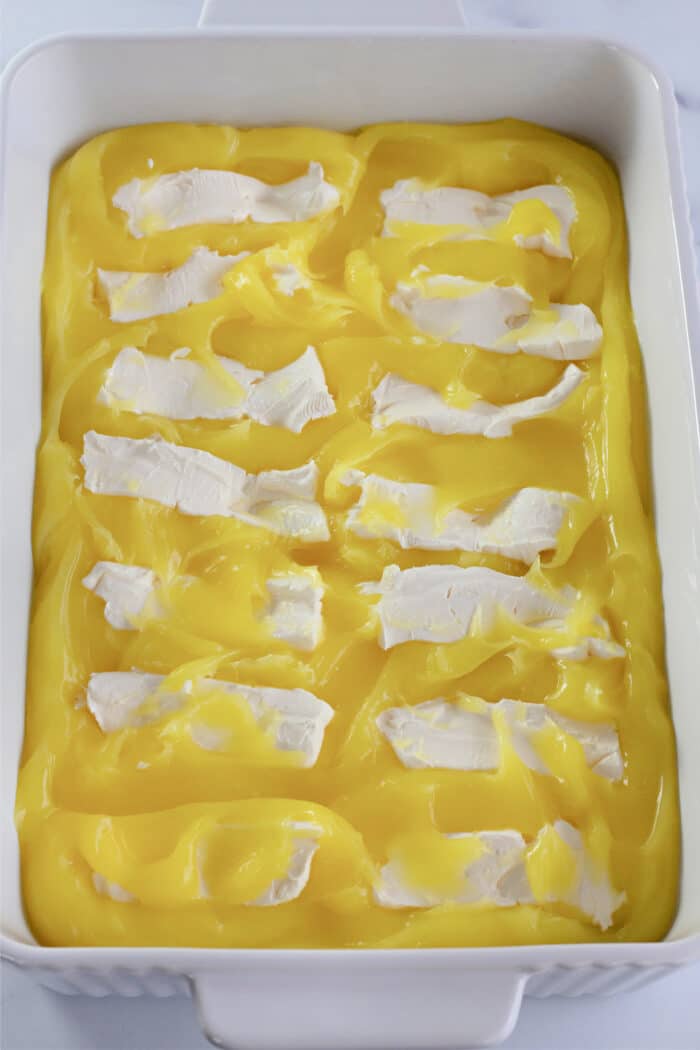 柠檬派馅料上的奶油奶酪切成薄片，放入烤盘中。