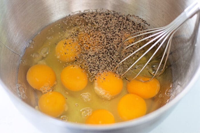 在金属碗中搅拌鸡蛋和调味料。